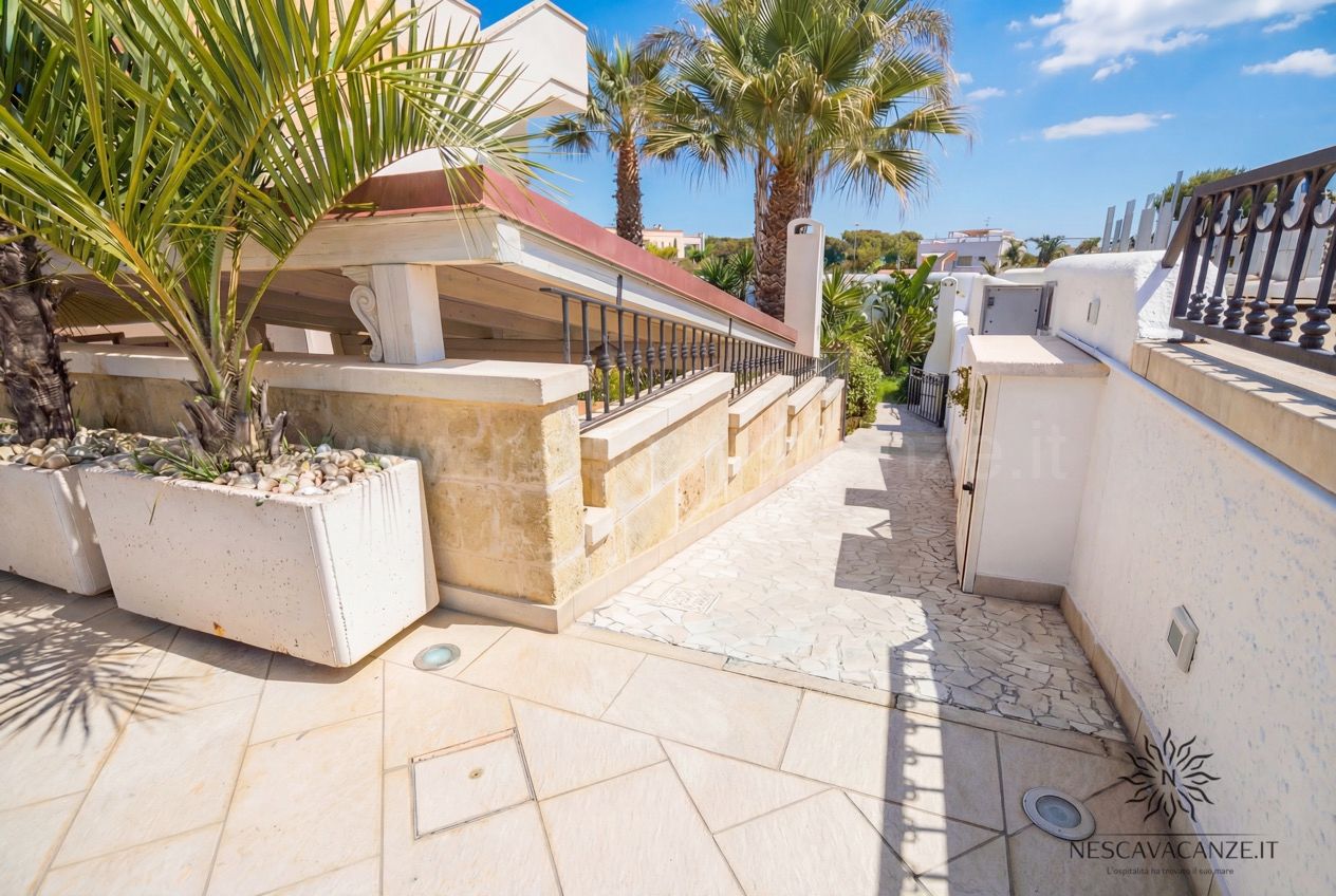 Casa Pescoluse 2 - vialetto laterale in pietra con palme, grandi fioriere bianche e pavimento chiaro