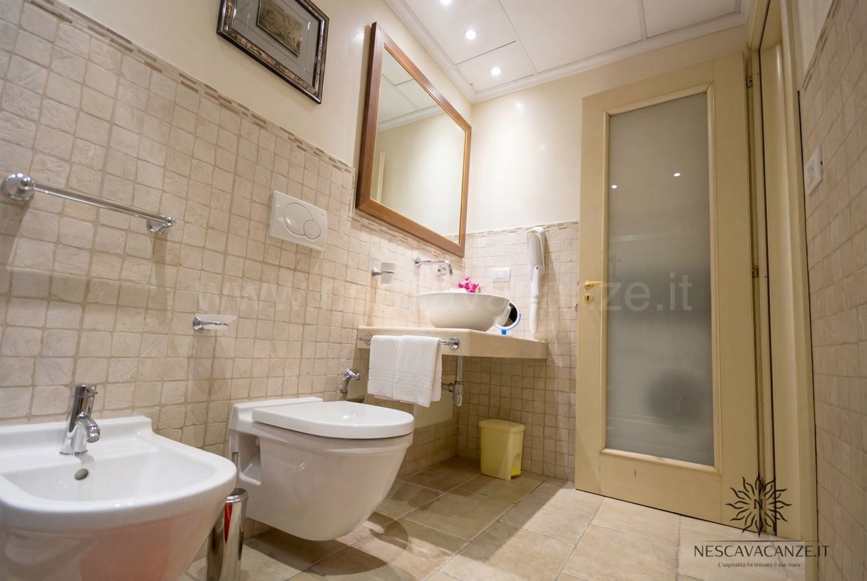 Casa Pescoluse 6 - bagno con mosaico beige, lavabo a bacinella, specchio, wc e bidet