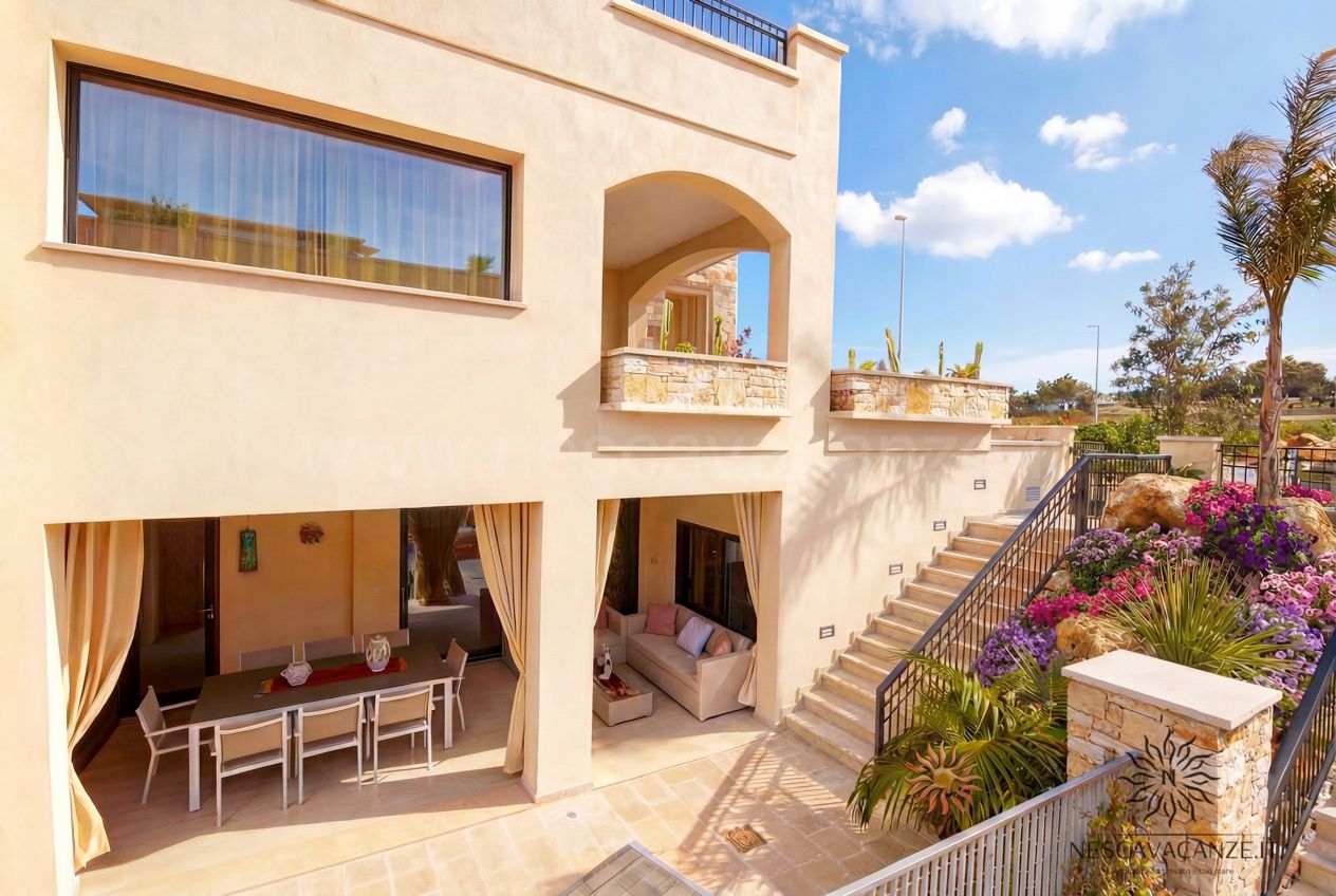 Casa Salento - retro della villa con veranda, tavolo da pranzo, divano e scala in pietra tra i fiori