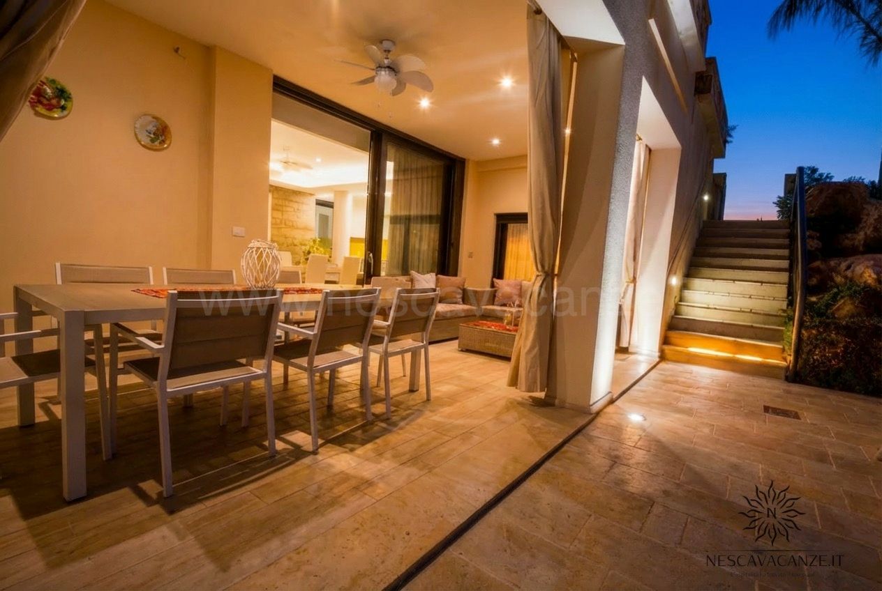 Casa Salento - veranda serale con tavolo, divano e scala in pietra illuminata al tramonto