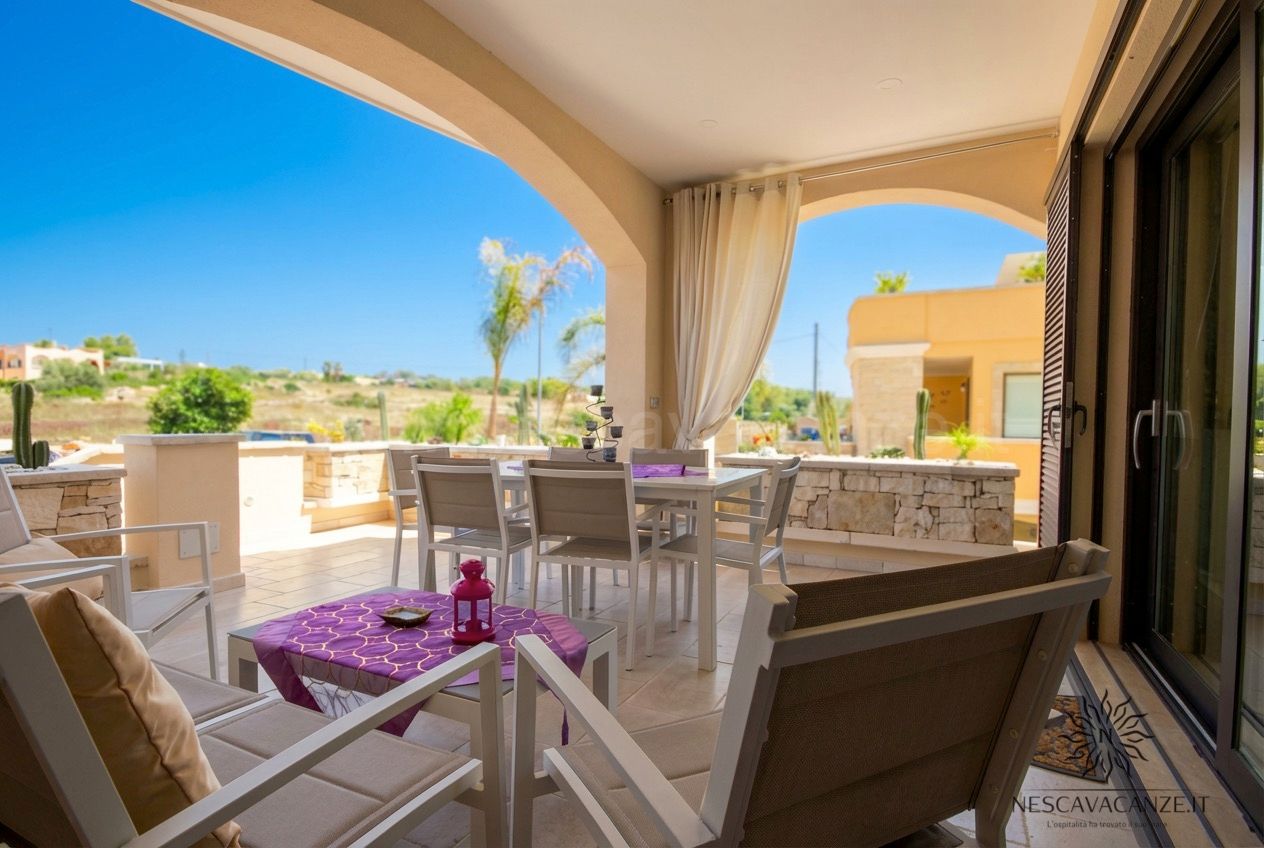 Casa Giglio - veranda con tavolo, poltrone e vista sulla campagna sotto cielo azzurro