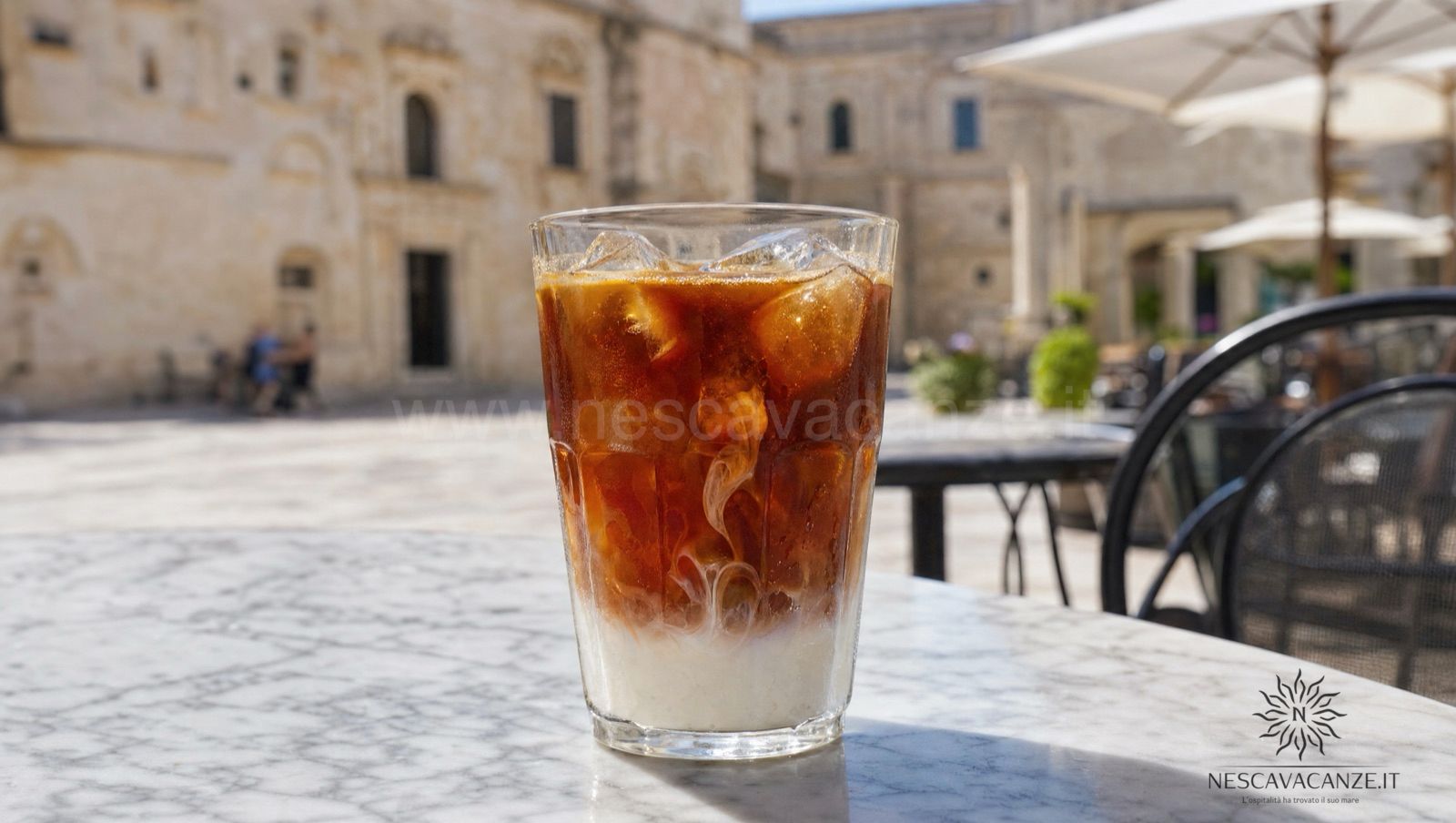 Caffè leccese in ghiaccio: espresso caldo e zuccherato versato su cubetti di ghiaccio con un dito di latte di mandorla, in un bar di una piazza salentina assolata