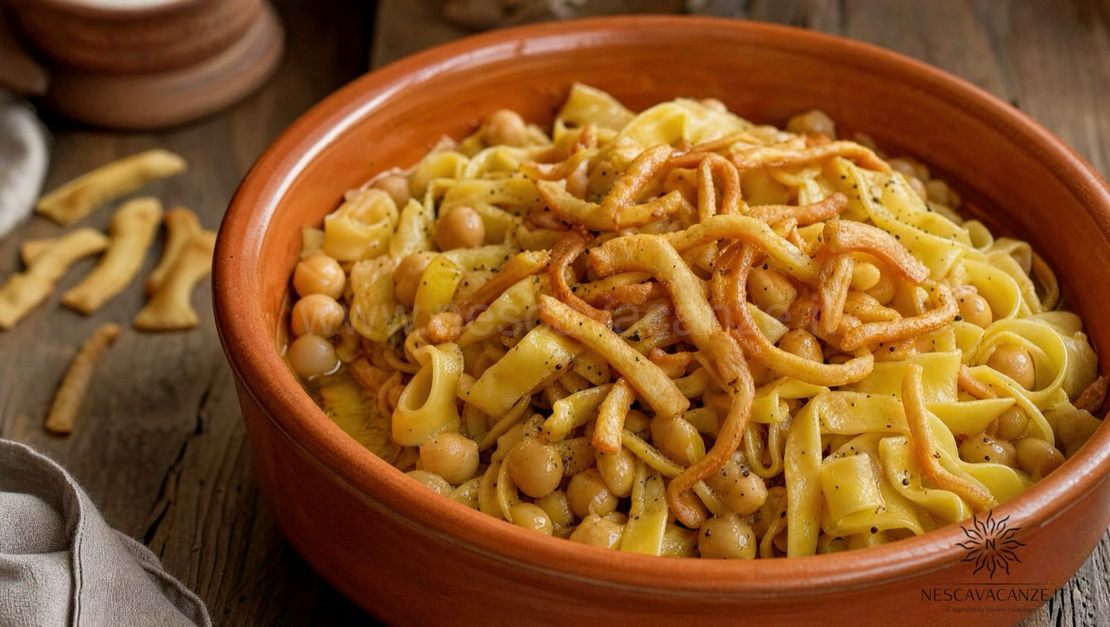 Ciceri e tria, pasta fresca all'uovo con i ceci in una ciotola di terracotta, con strisce di pasta fritta croccante sopra e una macinata di pepe nero