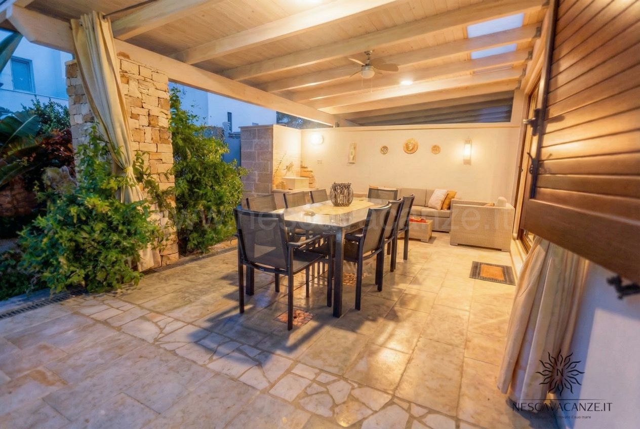 Casa Dune - patio esterno coperto con tavolo da pranzo in vetro, sedie nere, divano e un ventilatore a soffitto