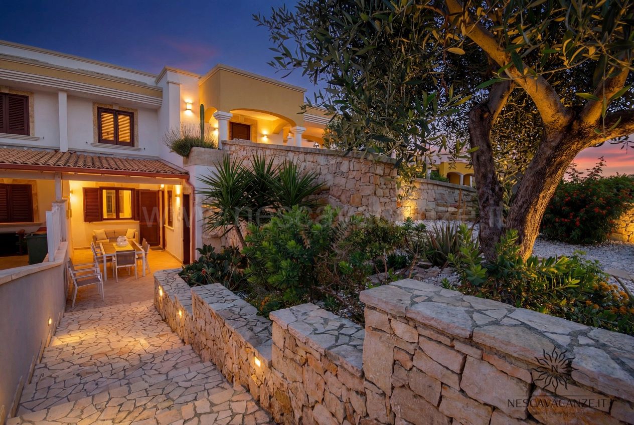 Casa Pescoluse 9 - esterno della villa al tramonto con muretti in pietra, giardino e veranda illuminata
