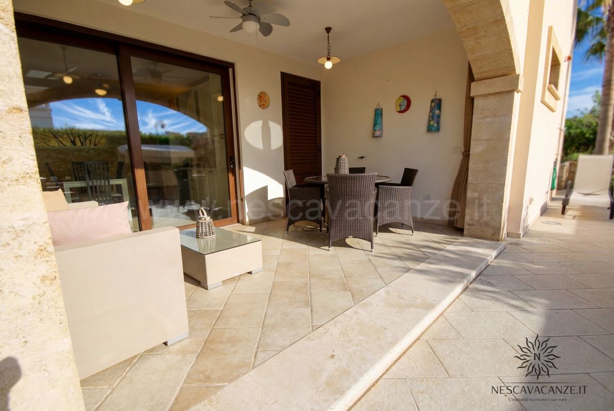Casa Pescoluse 6 - veranda coperta con divano bianco, salotto in rattan e vetrata scorrevole