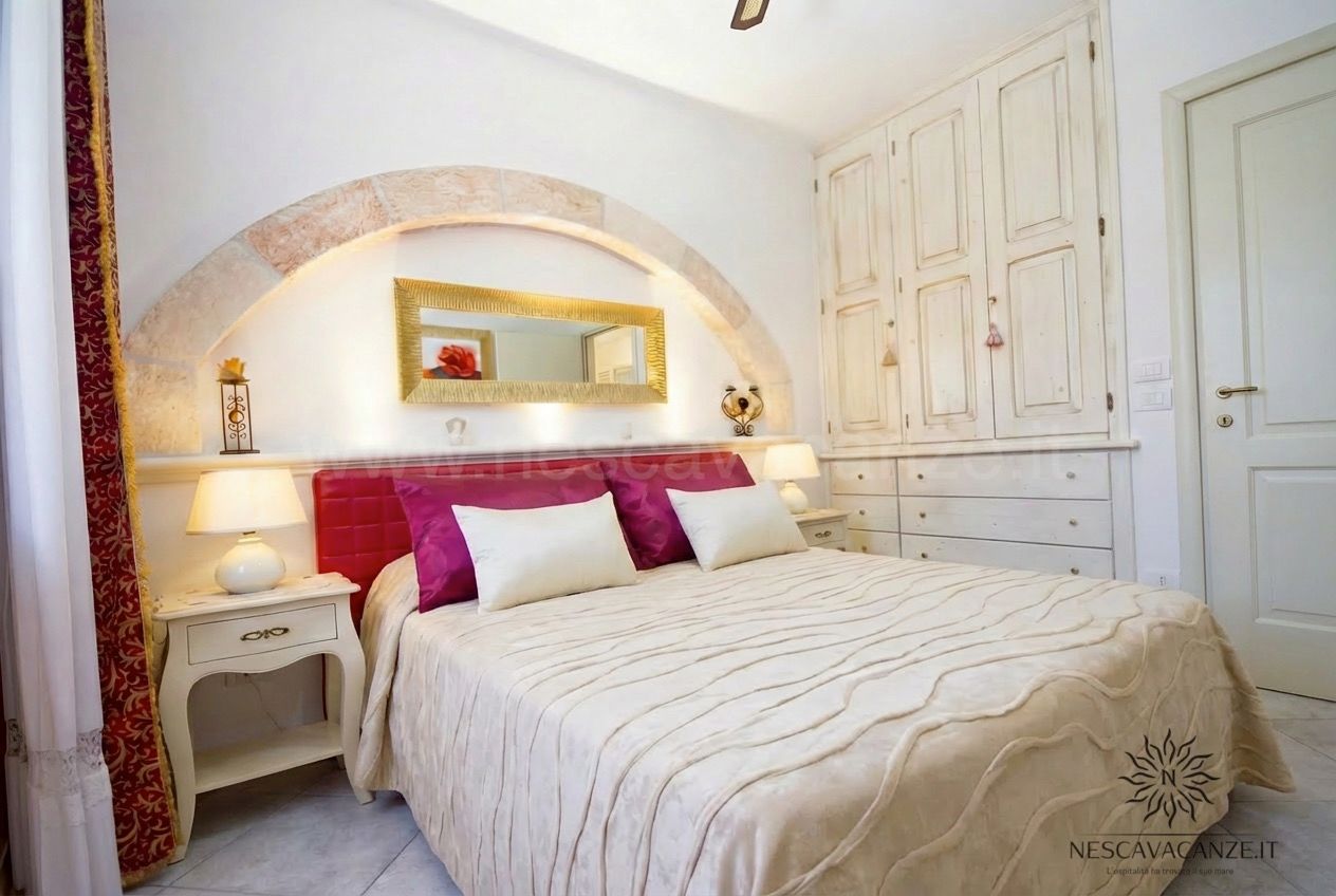 Casa Pescoluse 7 - camera matrimoniale con testiera fucsia, armadio bianco e specchio dorato