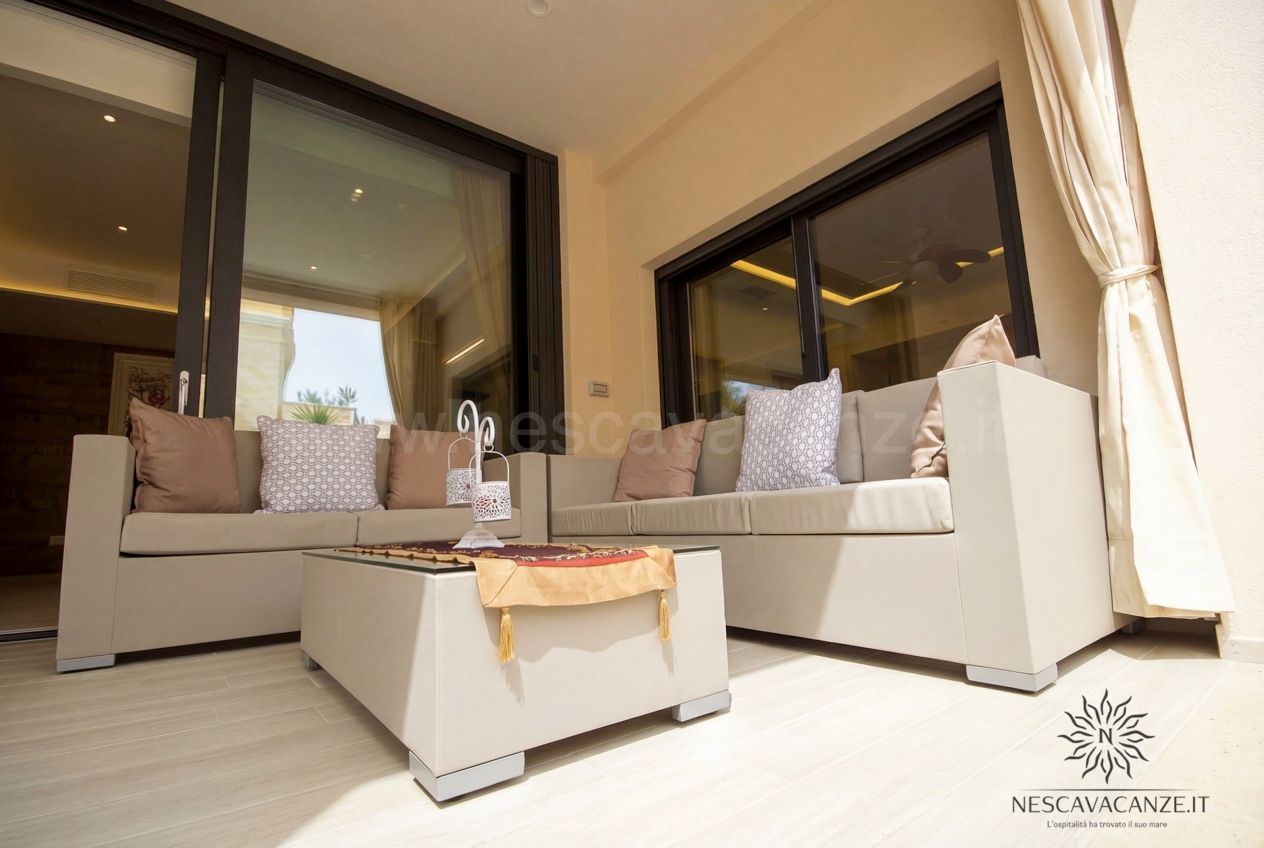 Casa Salento - salottino esterno in veranda con due divani beige, cuscini e tavolino basso