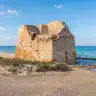 La torre di Torre Rinalda sulla spiaggia, con il mare mosso alle spalle