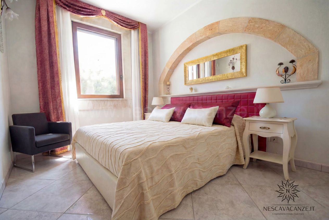 Casa Pescoluse 7 - camera matrimoniale con testiera fucsia, arco, specchio e poltrona