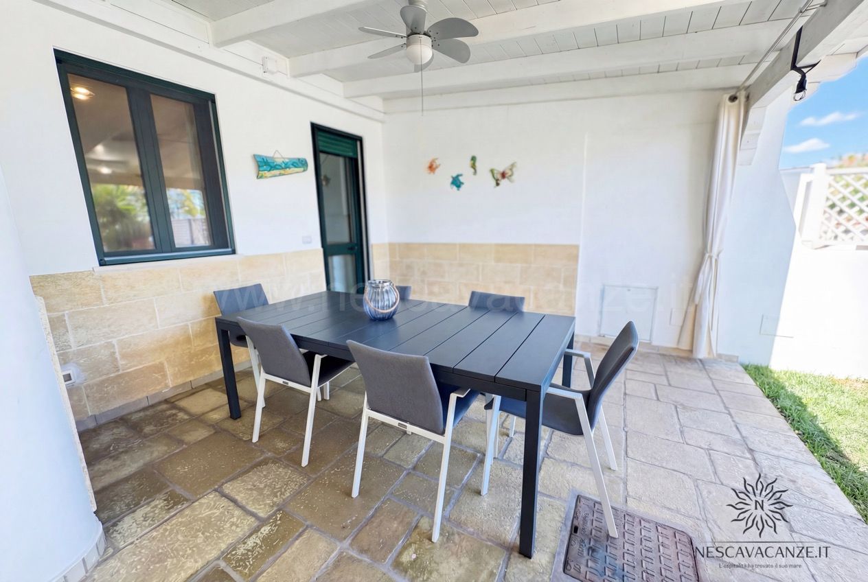 Casa Sabbia Oro - veranda coperta con tavolo, sedie, ventilatore a soffitto e decori marini a parete