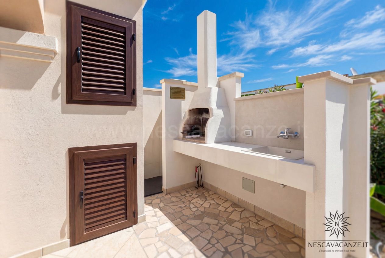 Casa Pescoluse 8 - Zona barbecue esterna con forno in muratura, lavello e pavimento in pietra
