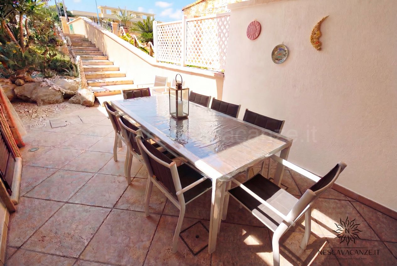 Casa Pescoluse 9 - terrazza con lungo tavolo da pranzo in vetro, sedie, scala e decori a sole