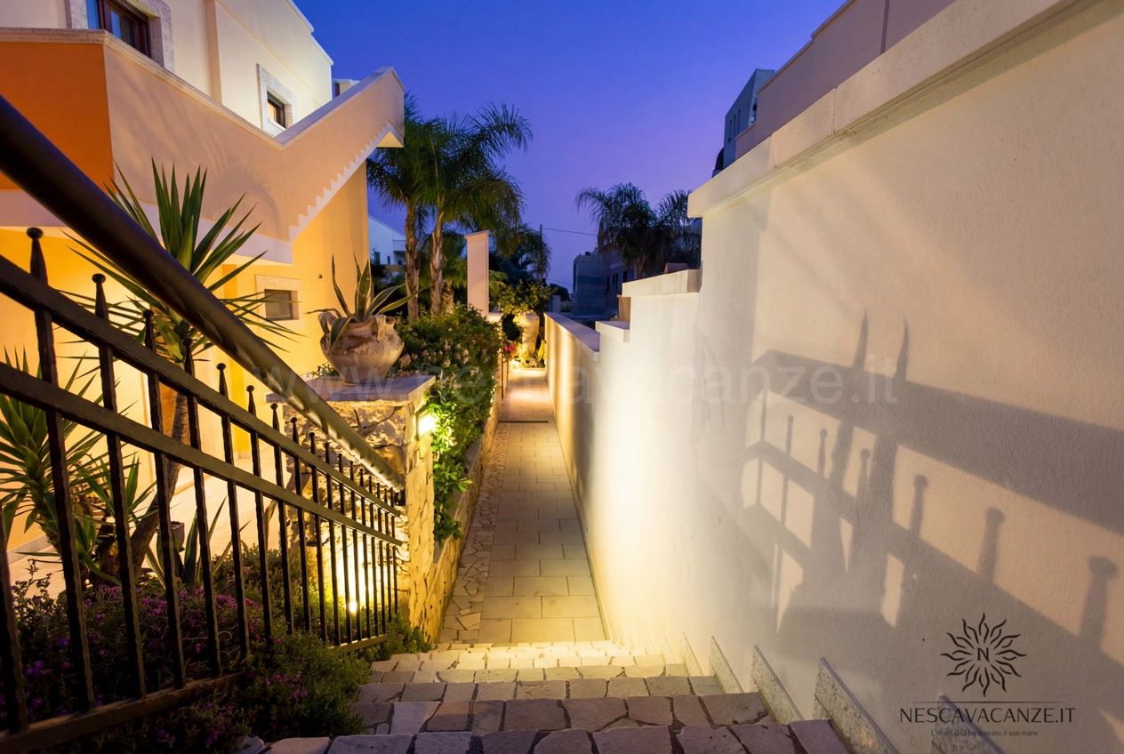 Casa Pescoluse 7 - vialetto d'ingresso illuminato al crepuscolo con scala e palme