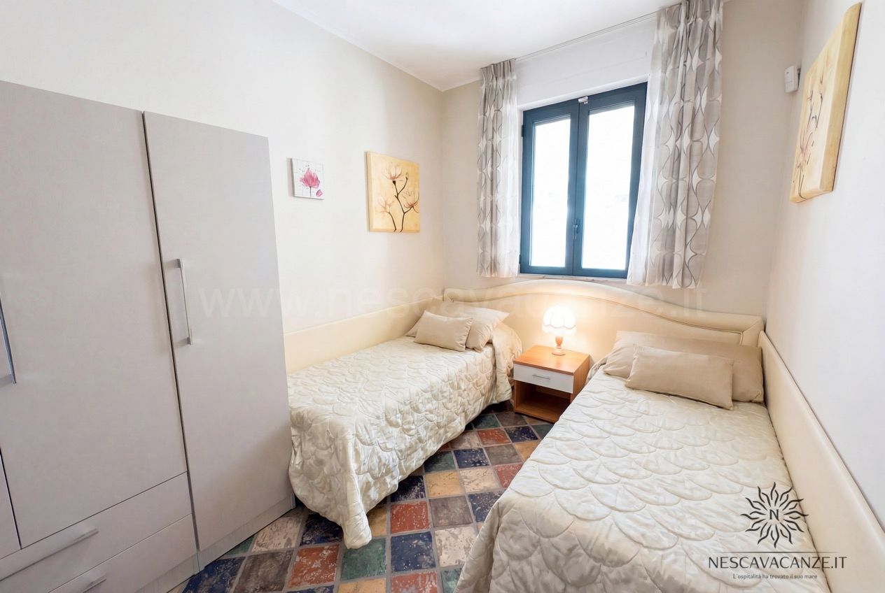 Casa Sabbia Oro - cameretta con due letti singoli, armadio, finestra e quadri floreali