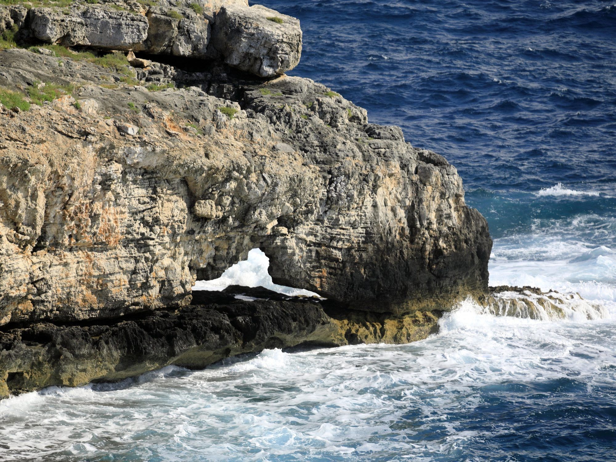 Uno scoglio con un arco scavato dalle onde sotto la costa di Punta Ristola, nel mare mosso