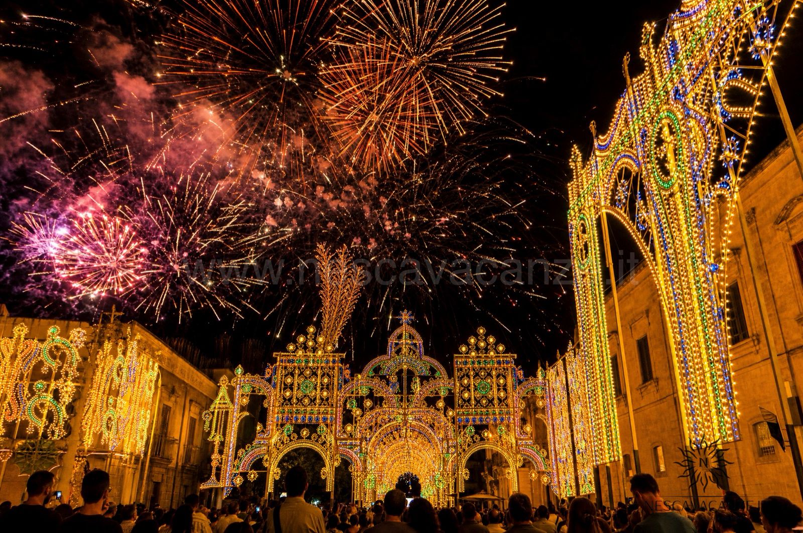 Fuochi d'artificio nel cielo sopra le luminarie illuminate di una festa patronale salentina