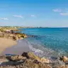 La piccola spiaggia di Mancaversa tra gli scogli bassi, con le onde a riva
