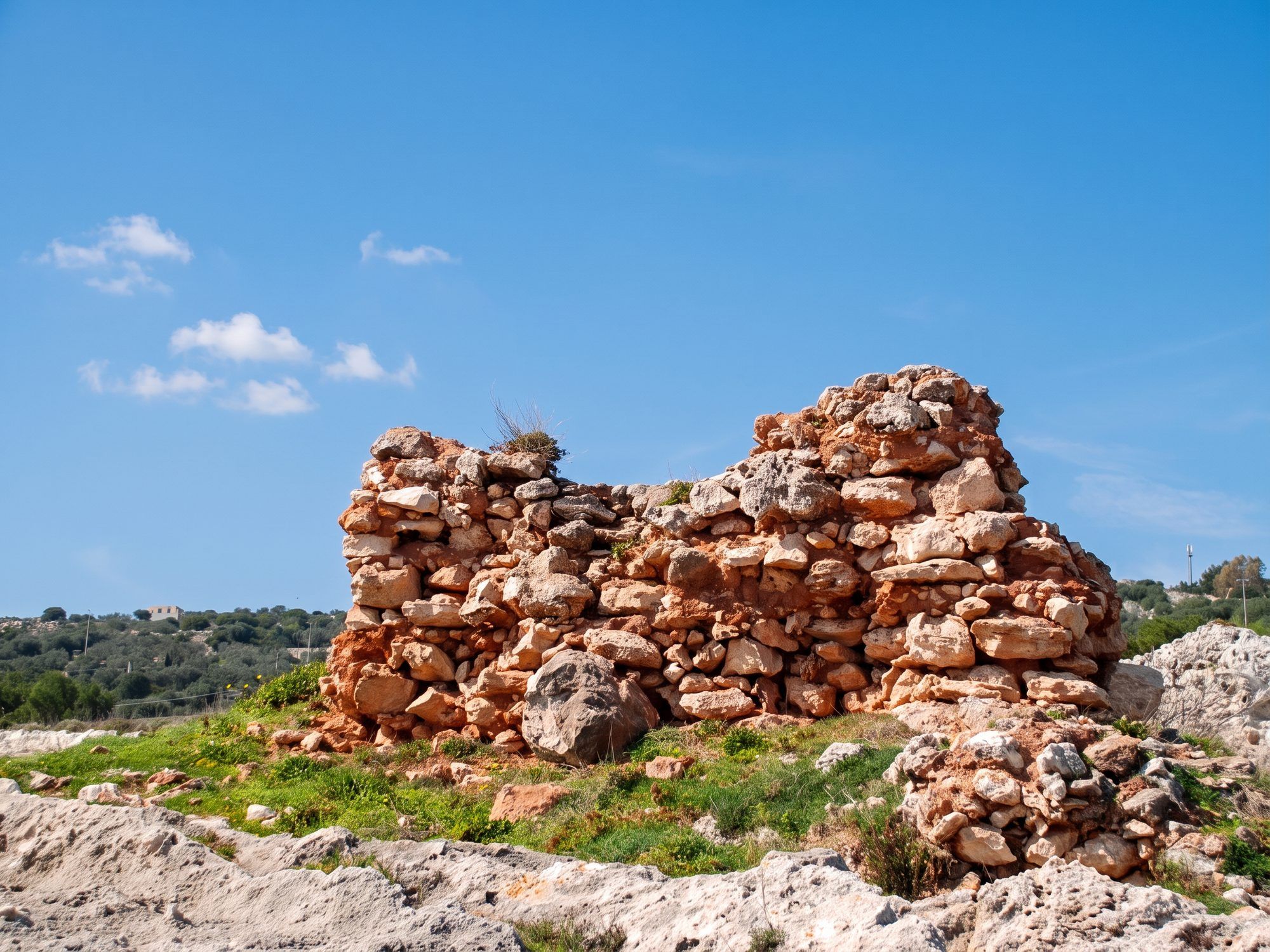 Il rudere in pietra della Torre del Porto di Novaglie sulla roccia, sotto il cielo azzurro