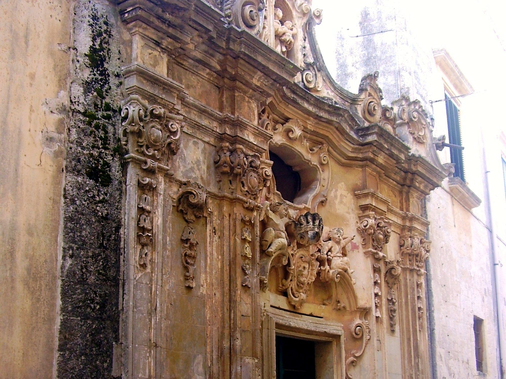 La facciata rococò della Cappella Arditi a Presicce, in pietra leccese scolpita, nella via stretta