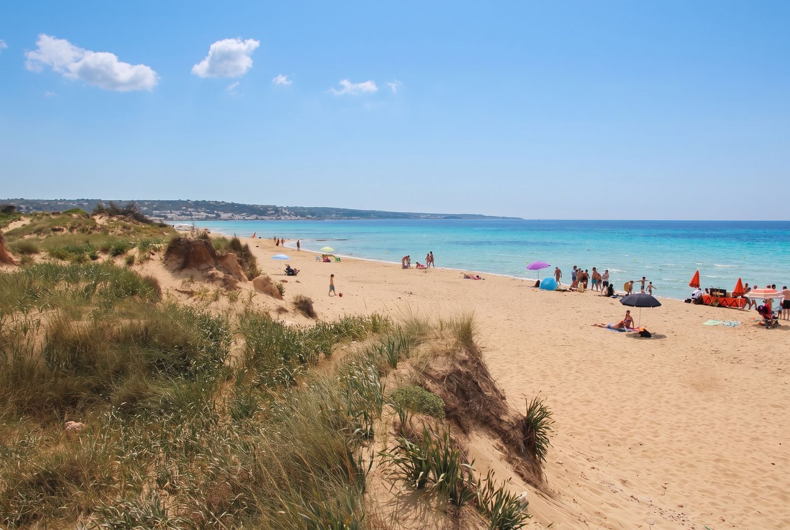 Spiaggia libera di Pescoluse vista dalle dune, con ombrelloni sparsi sulla sabbia e il mare turchese