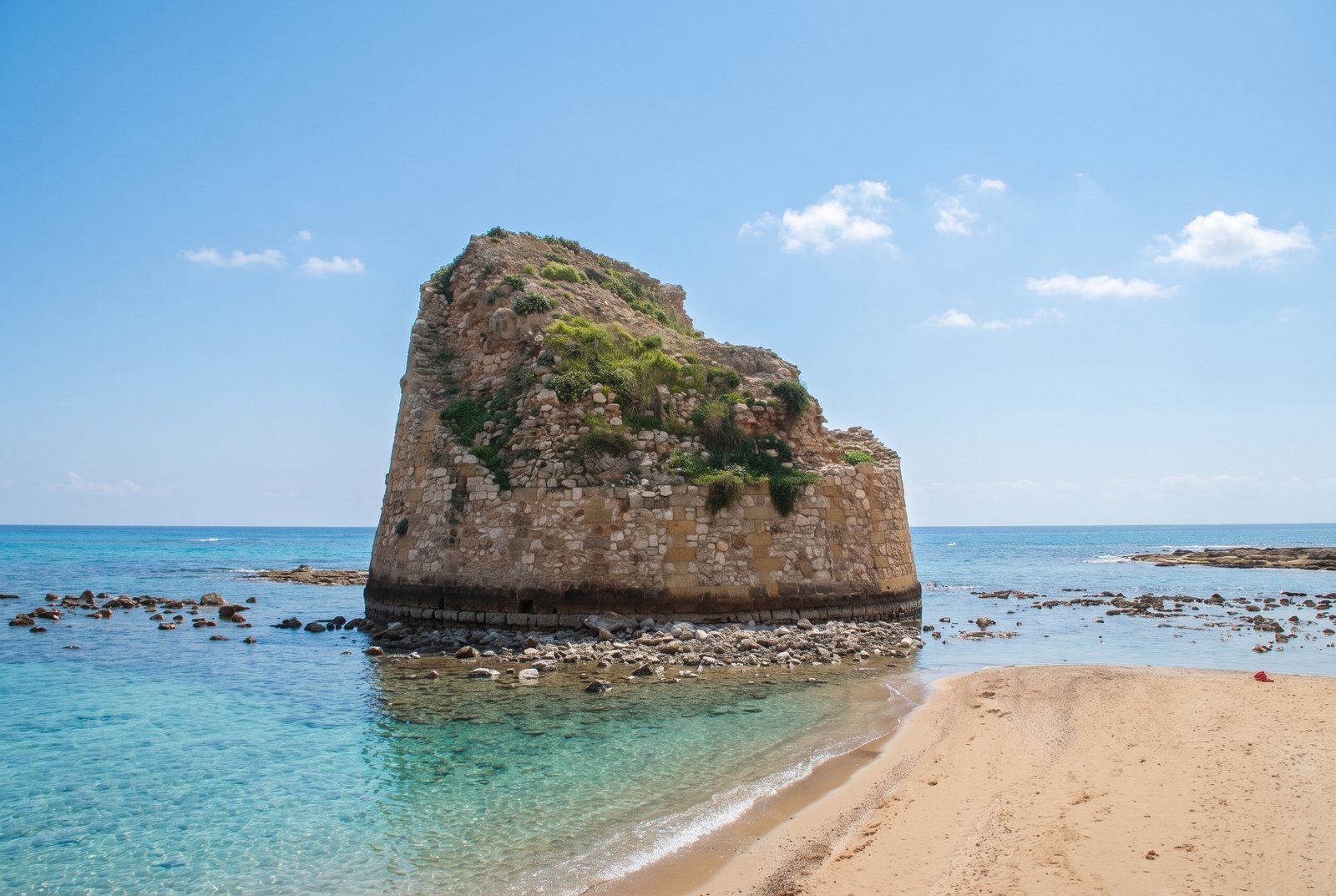 La torre di Torre Pali nel mare, con la lingua di sabbia e l'acqua bassa e trasparente
