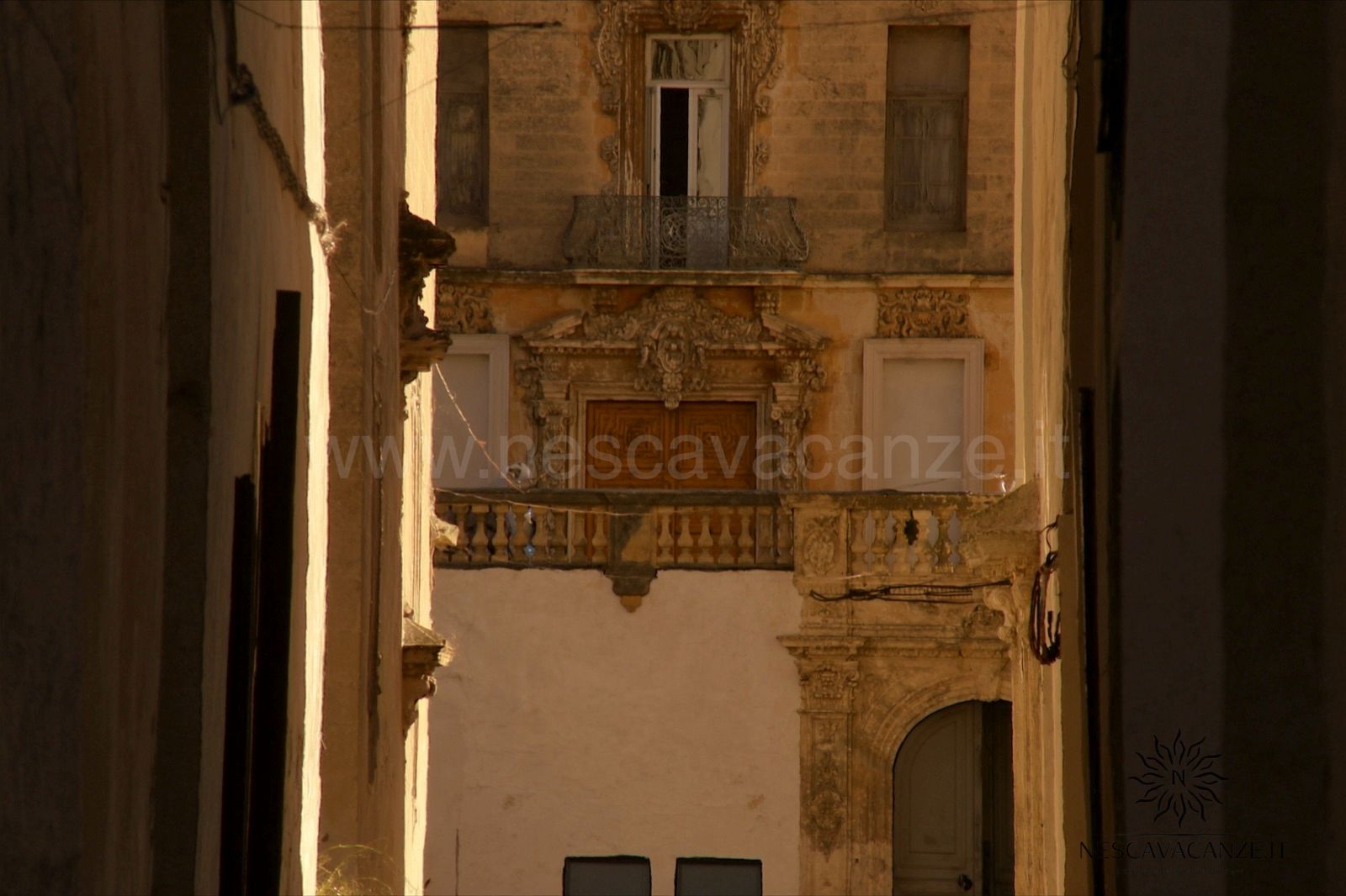Vicolo del centro storico barocco di Lecce con balconi e portali scolpiti in pietra leccese dorata