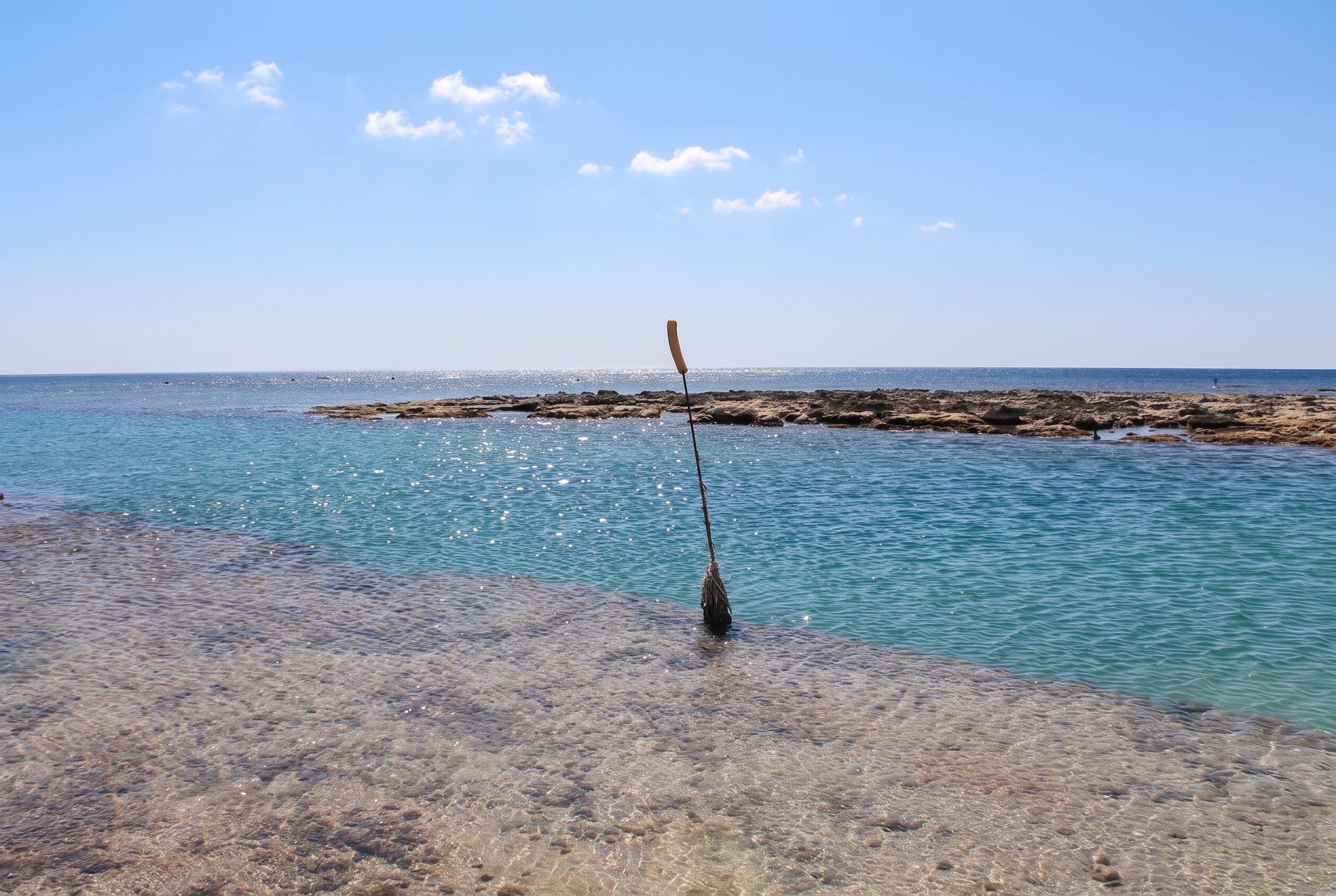 Acqua bassa e trasparente a Torre Pali, con gli scogli piatti che affiorano davanti alla riva