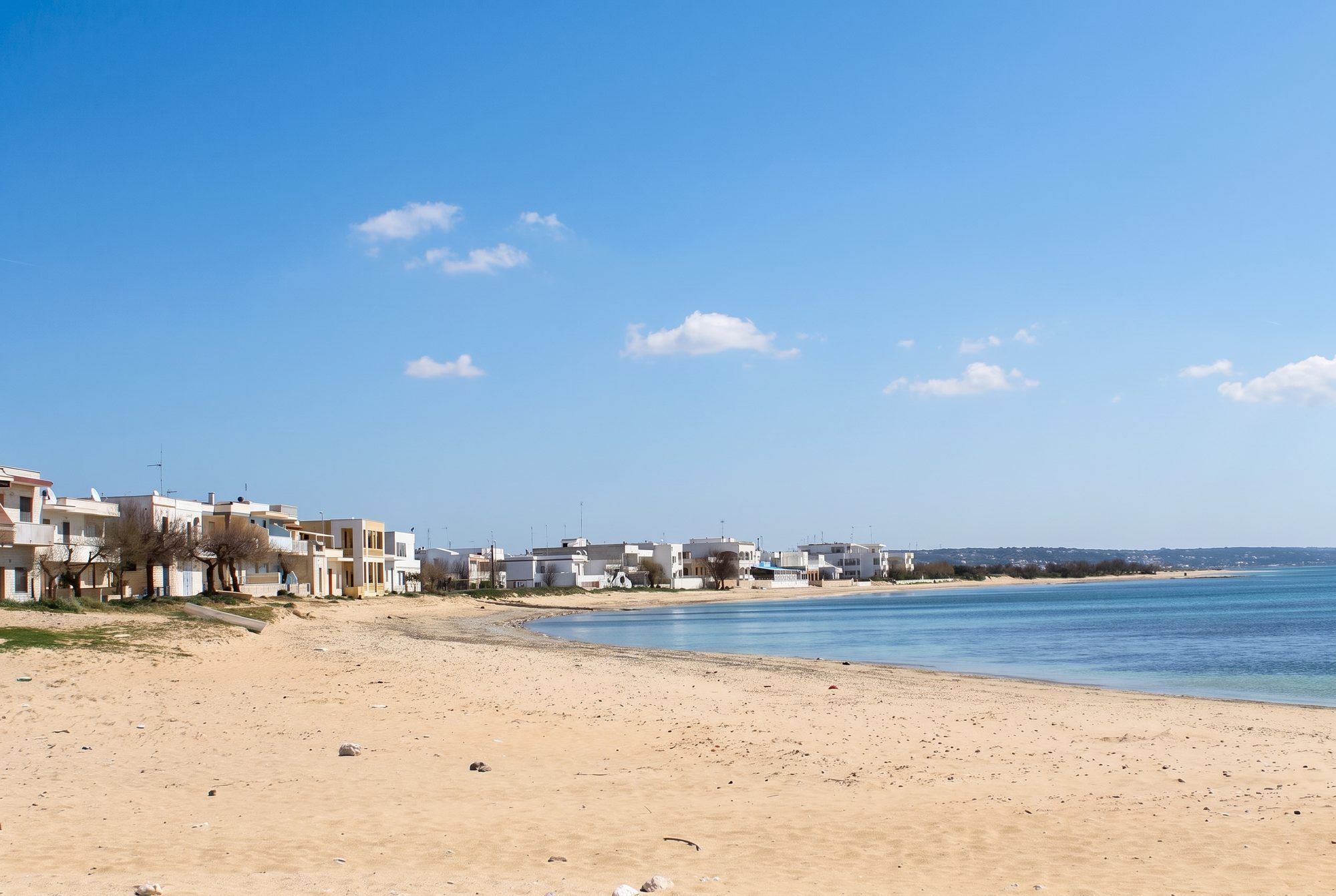 La spiaggia di sabbia di Torre Pali con le case bianche del lungomare e il mare calmo