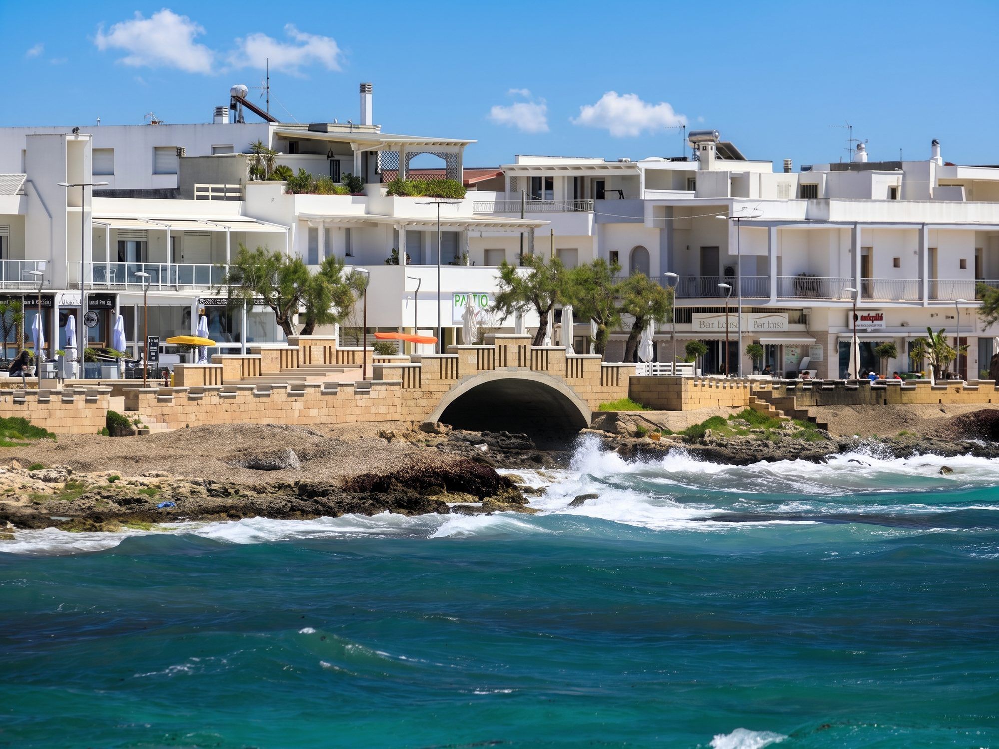 Il lungomare di Torre San Giovanni con le case bianche e il ponte ad arco sul canale che sbocca in mare